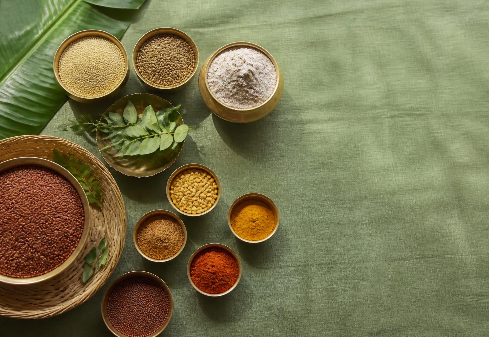 Organic Tamil pantry staples in brass bowls on green linen